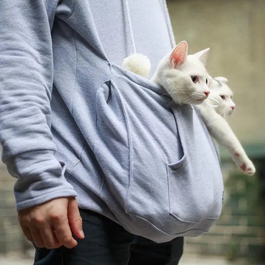 a man wearing a nice cotton light blue hoodie with kangaroo pocket that's holding 2 cute white cats in it