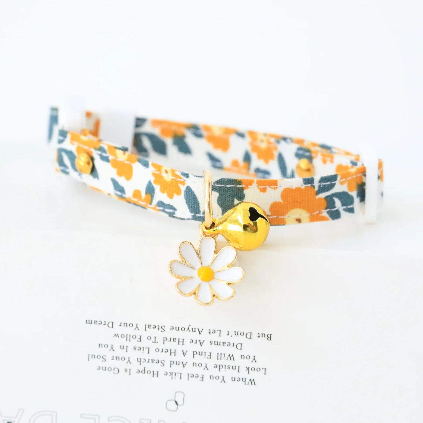 cute white cat collar with orang flowers on the collar, a bell and a white flower shape attached 