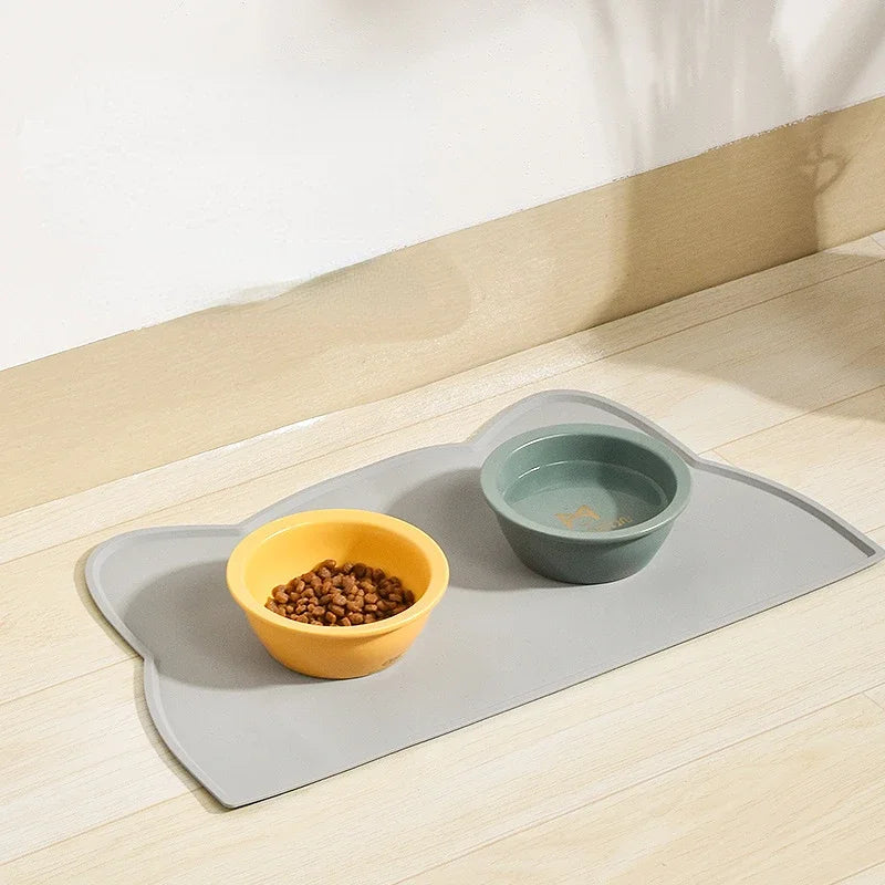 grey rubber cat mat that is shaped like a cat's head with bowls on it
