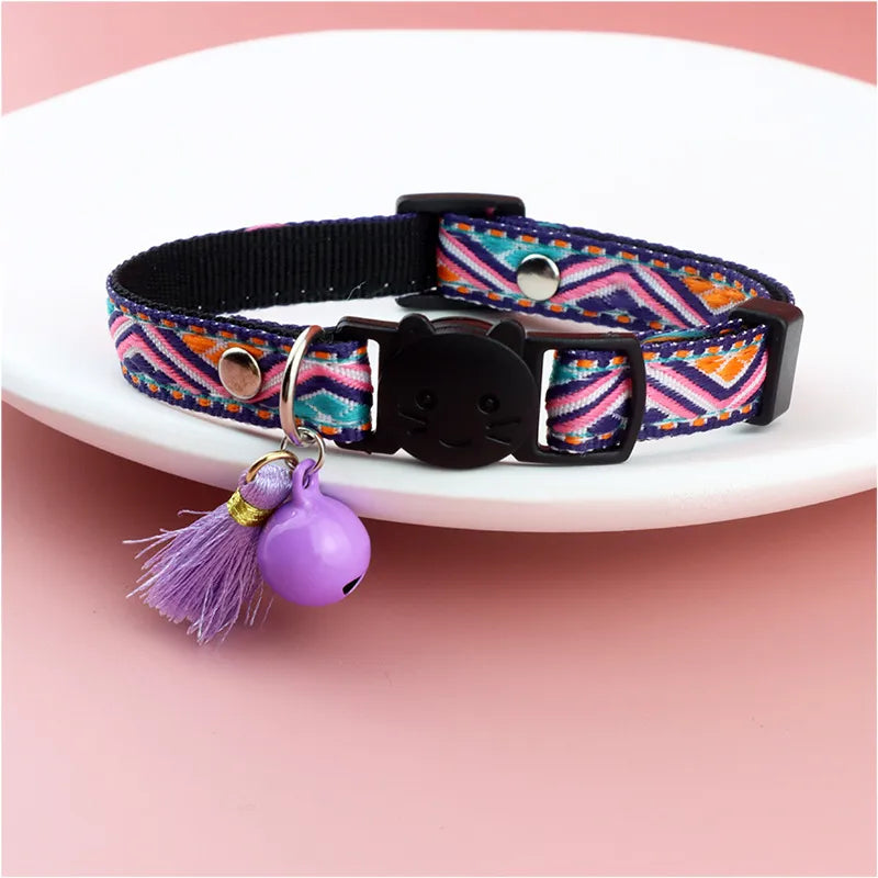 a purple striped colorful color with a cat face for cats with a jingle bell on it