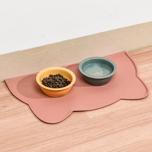pink rubber cat mat that is shaped like a cat's head with bowls on it