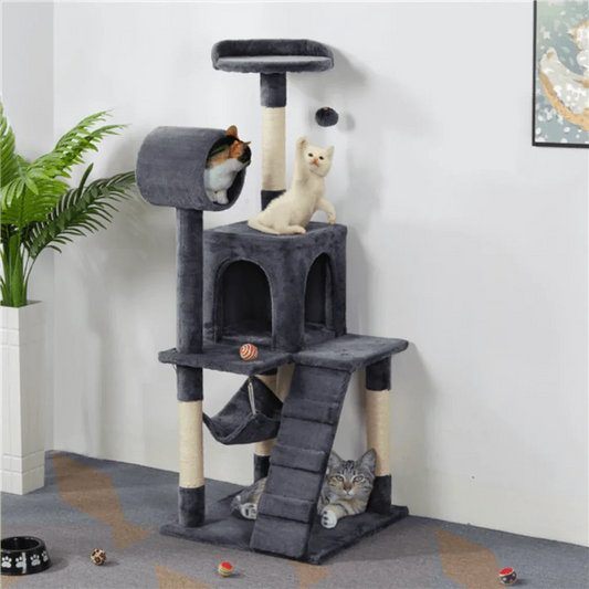 three cute cats sitting and playing on a dark gray cat tree stand in the living room 