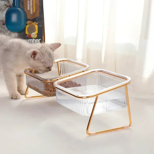 a cute white cat eating off a luxurious clear bowl with gold stand on it 